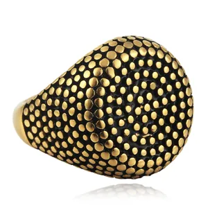 Detail van een gouden punkring met dichte cirkelvormige noppen en zwart email op de band