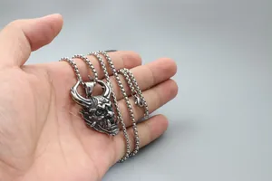 Macro shot of silver demon pendant with detailed mask carving and sturdy box chain