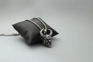 Detailed view of silver Hannya demon pendant necklace displayed on black satin cushion