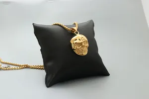 Close-up of golden skull pendant with detailed relief on a black leather cushion