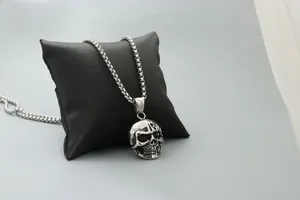 Detailed view of silver skull pendant with mechanical carvings on a black jewelry pillow