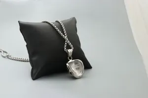 Detail view of silver punk skull pendant with ball chain on black leather pillow