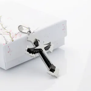 Detailed close-up of a silver gothic cross pendant with black wings on a jewelry box