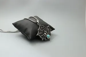 Détail d'un collier toile d'araignée avec pierre turquoise bleue sertie sur l'acier