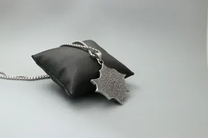 Détail d'un pendentif bouclier punk argenté avec texture métallique martelée sur chaîne