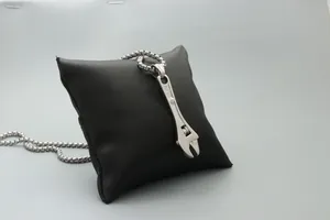 Detailed macro view of creative wrench pendant on box chain with metallic polished finish