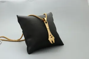 Detail of creative gold wrench pendant on box chain displayed on a black cushion