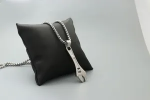 Macro view of polished silver wrench pendant with detailed industrial metal design