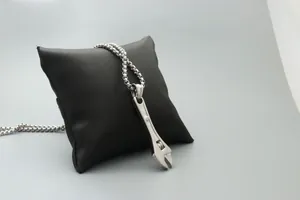Macro detail of silver wrench pendant necklace with adjustable nut and beaded chain