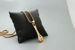 Detailed close-up of a golden wrench pendant necklace on a black display pillow