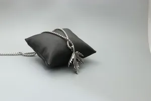 Detail showing the intricate maple leaf pendant texture on a silver box chain