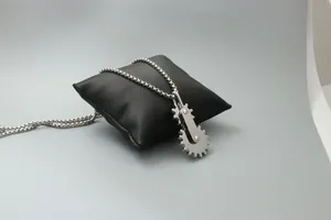 Gros plan du pendentif engrenage industriel avec chaîne à billes sur satin noir