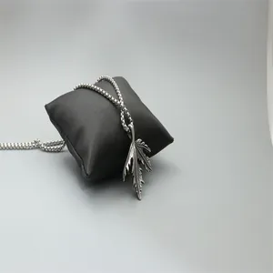 Vintage leaf pendant necklace in titanium steel hanging on black jewelry pillow