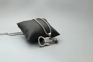 Détail du collier pendentif guitare crâne décapsuleur sur un coussin en satin noir