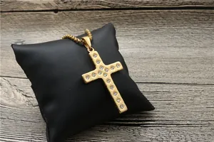 Close-up of golden cross pendant featuring sparkling white zircons on a black cushion