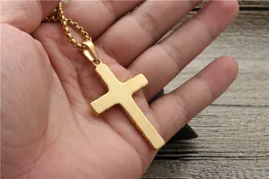 Detail of a golden cross pendant necklace featuring textured edges on a bead chain