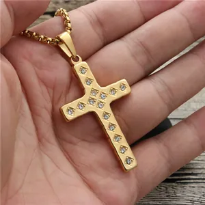 Handheld gold cross pendant necklace with sparkling cubic zirconia on box chain