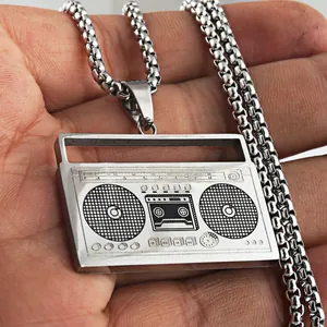 Detalle del colgante de radio retro plateado en la mano con una cadena de caja