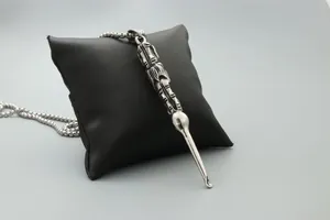 Detailed close-up of retro silver stainless steel ear spoon pendant on a black leather pillow