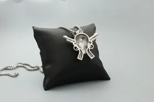 Detalle de colgante de calavera y pistolas plateadas con cadena de bolas en cojín