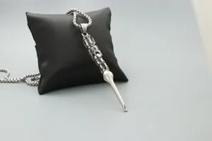 Close-up of vintage tribal engraved earspoon pendant on box chain over black pillow