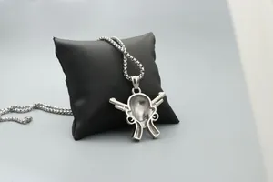 Primer plano de un colgante de calavera y pistolas cruzadas sobre soporte de cuero