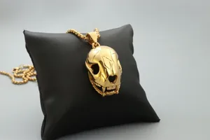 Gros plan d'un collier avec pendentif crâne animal doré sur support en cuir noir