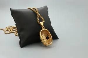 Détail d'un pendentif tête de mort doré avec chaîne à mailles carrées polie sur présentoir