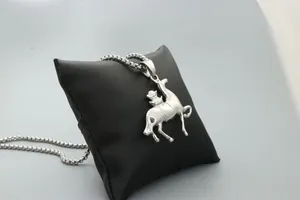Detailed close-up of a silver horse rider pendant with a metal bead chain on black satin