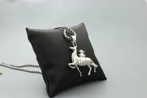 Macro detail of silver running horse pendant necklace on black display cushion