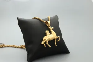 Detail shot of golden horse pendant on box chain displayed on black pillow background