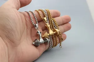 Detail of barbell dumbbell pendants in silver and gold colors held by hand for gym theme