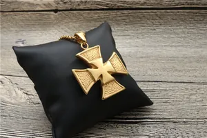 Close-up of golden Iron Cross pendant with hammered texture on black leather pillow