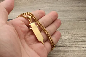 Close-up of golden syringe pendant necklace on a box chain held in hand for scale