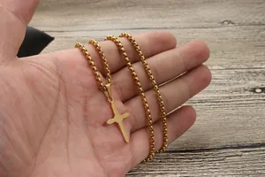 Nahaufnahme der vergoldeten Kreuzkette mit Box-Kette, in der Hand über Holz gehalten
