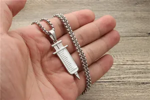 Detailed view of silver stainless steel syringe pendant necklace held in hand