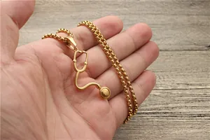 Detailaufnahme einer goldenen Stethoskop-Halskette, die über Holz gehalten wird