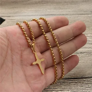 Minimalistische goldene Kreuzkette mit klassischer Boxkette auf einem Holzuntergrund