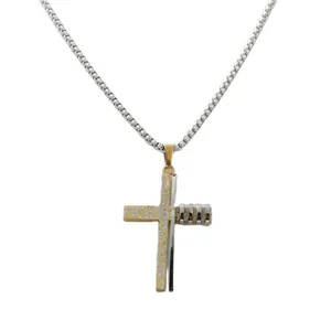 Détail du pendentif croix en acier bicolore avec finition dorée à texture craquelée