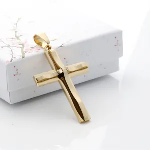 Detalle del colgante de cruz dorada pulida apoyado en una caja de regalo floral