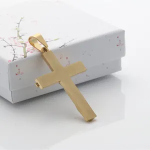 Detalle de un colgante de cruz de oro cepillado sobre un joyero blanco con flores
