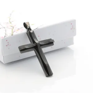 Detalle de un colgante de cruz negra de doble capa con bordes facetados en caja de regalo