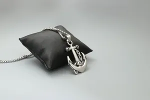 Détail d'un pendentif ancre de pirate en argent avec chaîne sur un coussin en soie noire