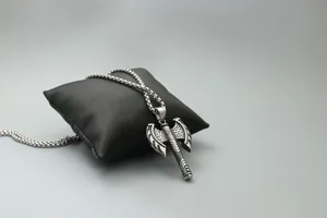 Detailed macro view of a vintage silver double-headed axe pendant with scale engraving