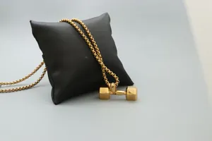 Makro-Detail des goldenen Hantel-Anhängers an einer Gliederkette aus Edelstahl