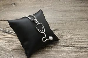 Detail of silver stethoscope pendant necklace on black leather cushion display