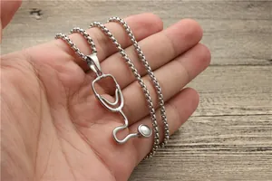 Macro shot of silver stethoscope pendant necklace with square cable chain held by hand