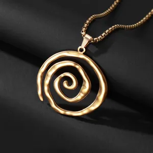 Collier à pendentif spirale dorée géométrique avec chaîne box sur fond texturé sombre