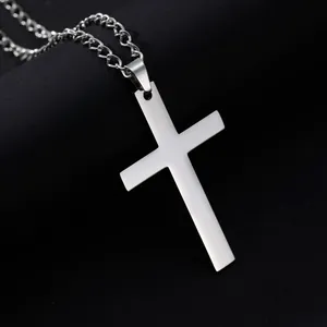 Gros plan du pendentif croix argenté montrant la texture fine de l'acier brossé