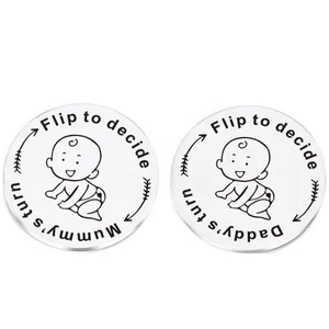 Macro detail of stainless steel baby decision coin showing Daddy's and Mummy's turn